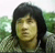 Pixelated portrait of a person with long dark hair against a green and white background, rendered in low-resolution digital style.