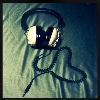 Pixelated image of black over-ear headphones with light-colored earcups resting on a textured fabric background.