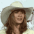 Static pixelated image of a person wearing a wide-brimmed hat with long brown hair, smiling against a light background.
