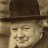 Static pixelated image of a person wearing a dark brown fedora hat, light-colored face, and dark clothing against a blurred background.