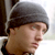Static 50x50 pixel buddy icon showing a close-up of a person's head and shoulders with dark hair, wearing a gray beanie hat against a light background.