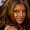 A static close-up of a person with long wavy light brown hair, wearing a white strap top, against a blurred background.