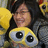 A pixelated image shows a person with dark hair wearing a yellow top with large cartoon eyes on the chest, holding a yellow object.