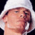 Two side-by-side pixelated images of a person wearing white and blue head coverings, one with eyes closed and the other holding a microphone.