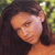 A pixelated close-up of a person with dark hair and light skin, showing a partial face with closed eyes and a neutral expression against a blurred green background.