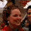 A woman with brown hair in a red outfit smiles in a pixelated image with visible motion blur.