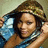 A person with light brown skin wears a blue garment and patterned headwrap, holding the fabric near their face in six