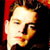 Static pixelated image of a person's face with warm lighting and red background elements, rendered in low-resolution style typical of early 2000s digital icons.