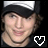 A person wearing a black cap with white brim and dark clothing, smiling slightly in two side-by-side frames.