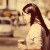 Pixelated image of a person with long dark hair in profile, wearing light-colored clothing against a blurred background.