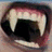 Pixelated close-up of a mouth with prominent fangs and red lips, surrounded by black background text in red pixel font.