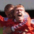 Two pixelated figures in red sports jerseys embracing on a soccer field with blurred background.