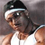 A pixelated figure wearing a black cap with a white stripe, dark sunglasses, and a white sleeveless top, with a blurred background.