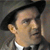 Static 50x50 pixel icon showing a close-up of a person's face with dark hair, wearing a white shirt and dark jacket against a gray background.