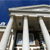 A pixelated image of a classical building facade with columns under a blue sky, showing architectural details and partial structural elements.