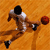 Pixelated static image of a basketball player in mid-air dribbling a ball against an orange background.