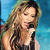 A pixelated image of a person with long wavy brown hair holding a black microphone against a blue background.