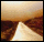 A pixelated image of a sand dune with a bright light source at the base, transitioning from brown to beige tones.