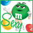 Green M&M character with white 'M' logo on chest, holding yellow bucket and green rope against white background.