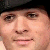 Static close-up of a person's face wearing a dark cap, with visible eyes, nose, mouth, and skin texture in pixelated rendering.