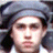 Pixelated close-up of a person wearing a dark blue cap with a light blue brim, long dark hair, and a white shirt against a dark background.