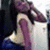 Pixelated image of a person with dark hair and purple clothing holding an object near their face.