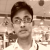 A pixelated grayscale portrait of a person with short dark hair, wearing glasses and a light-colored shirt against a blurred background.