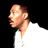 Pixelated static image of a person's profile with light skin tone, brown hair tied back, wearing white shirt against black background.