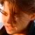 Pixelated close-up of a person's face with warm orange and brown tones, showing partial facial features and blurred background elements.