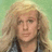 Pixelated portrait of a person with light brown curly hair, wearing dark clothing against a green background.