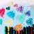 Pixelated image of a character with brown hair and glasses, wearing a black hoodie, against a light blue background with colorful heart shapes.