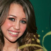A close-up of a person with light brown hair and blue eyes, wearing a white top against a teal background with yellow accents.