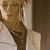 A split-screen image shows two figures with text elements; the left side features a person in light clothing against brown and white backgrounds, while the right displays another figure in dark attire on a plain background.
