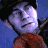Pixelated figure with light purple face, dark hair, and red garment against blue and black background.