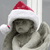 A pixelated figure wearing a red and white Santa hat with a small red pom-pom, holding a white object near its face against a gray background.