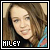 Pixelated square image of a person with light brown hair and fair skin, wearing dark clothing against a neutral background.