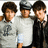 Three pixelated figures stand side-by-side, each with distinct clothing and hairstyles, against a light background.