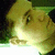 A pixelated image of a person's face with closed eyes and a slight smile, viewed from an angle against a green background.