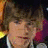 Two side-by-side pixelated images of a person with brown hair, one showing neutral expression and the other smiling.