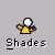 Pixelated figure in yellow shirt with white head, performing four distinct poses beneath text reading 'Shades' on gray background.