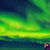 A pixelated static image with a gradient background transitioning from dark blue at the top to bright green and yellow in the middle, with a small multicolored pixel cluster in the bottom right corner.