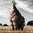Animated sequence of a giraffe standing in a savanna landscape with scattered trees under a cloudy sky.