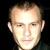 Static pixelated portrait of a person with light skin tone, short hair, and neutral expression against dark background.