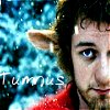 A static image shows a person with dark curly hair and blue eyes on the right, next to a blue and white nebula-like background with the text 'Tumulus' in white letters on the left.