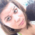Pixelated close-up of a person with light skin, brown hair, and a slight smile, wearing a dark top with a green accent.