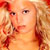Pixelated static image of a person's face with warm orange and red tones, showing partial facial features including eyes, nose, mouth, and hair against a blurred background.