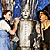 Pixelated image of three figures in a vertical arrangement with a blue and brown background, featuring a central figure in light clothing flanked by two smaller figures.