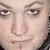 Pixelated close-up of a person's face showing eyes, nose, and mouth with light skin tone and dark hair visible on the right edge.