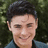 A pixelated image of a person with dark hair and a blue shirt, with text overlays on a green and gray background.