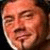 Pixelated close-up of a person's face with closed eyes and slight smile, next to red pixelated text on black background.